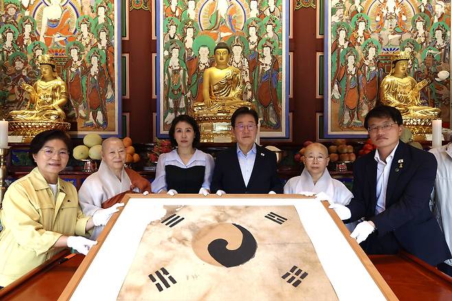 이재명 대통령과 김혜경 여사가 17일 서울 은평구 진관사를 방문해 2009년 진관사 복원과정에서 발견된 진관사 태극기를 보고 있다. 대통령실 제공