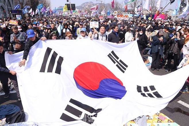 윤석열 전 대통령에 대한 헌법재판소의 탄핵이 인용되고 지난 4월 4일 종로구 일대에서 시민들이 대형태극기를 들고 포즈를 취하고 있다. ⓒ데일리안 방규현 기자