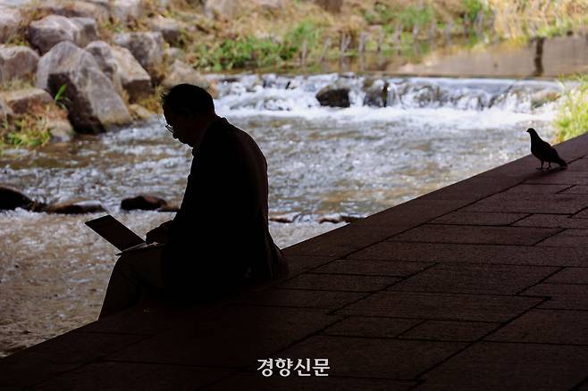 18일 서울 청계천에서 한 남성이 업무를 보고 있다. 2025.8.18 이준헌 기자