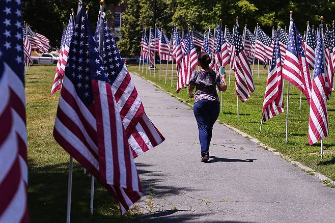 지난 6월25일 미국 매사추세츠주의 한 공원에서 한 여성이 성조기 사이를 걷고 있다. AP연합뉴스