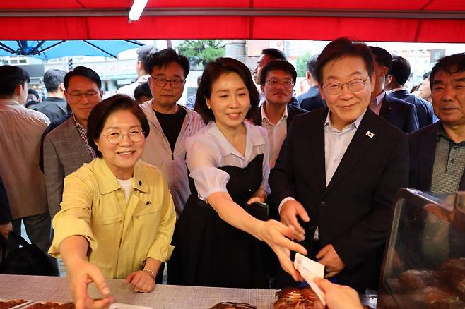 이재명 대통령 부부가 17일 김미경 서울 은평구청장과 연서시장을 찾아 소비쿠폰으로 물건을 사고 있다. [은평구 제공]
