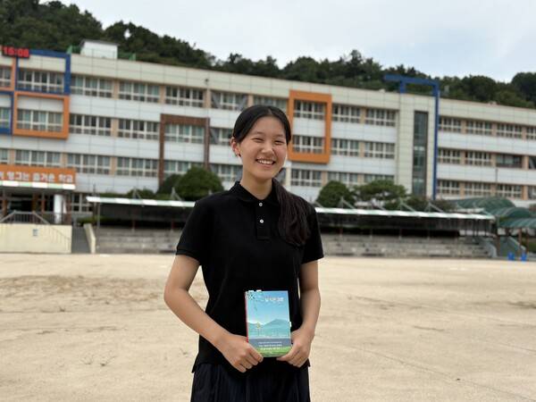 마산 양덕여중 2학년 손예진 작가가 자신의 학교에서 최근 출간한 소설 〈덜 익은 여름〉을 들고 웃고 있다. /주성희 기자