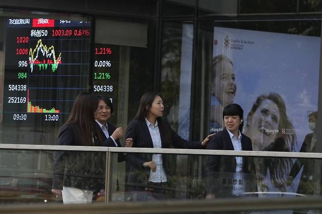 중국 베이징의 중심 거리에서 젊은 직장인들이 20일 뛰어 오르고 있는 주식 시황판을 배경으로 즐거운 표정으로 활보하고 있다. 뉴시스