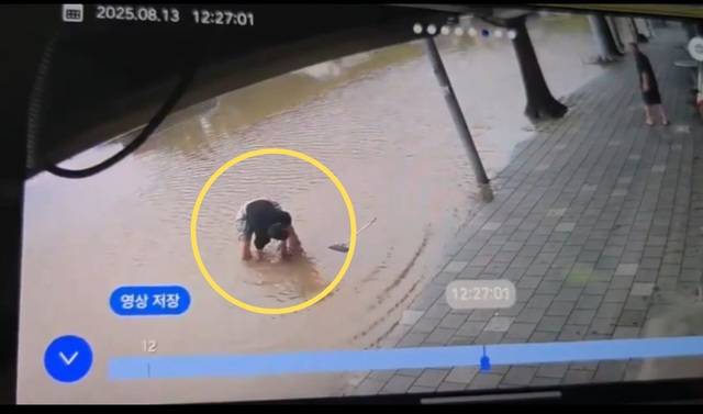 폭우로 물이 차오른 인천 부평구에서 두 아이의 아빠 김동희씨(31)가 흙탕물로 잠긴 도로의 배수구 덮개를 들어 올려 더 큰 물난리를 막았다. 독자 제공