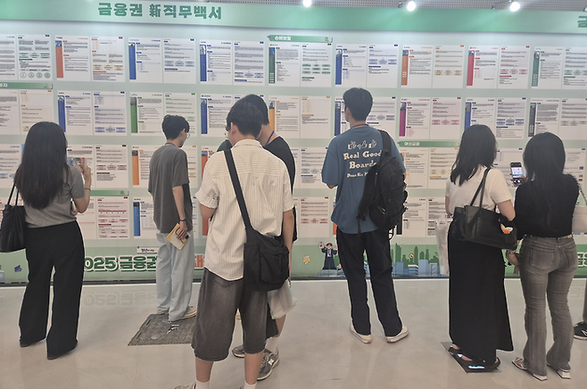21일 오후 1시께 ‘2025 금융권 공동채용 박람회’ 참석자들이 취업 관련한 게시물을 보고 있다. [사진 = 최종일 기자]
