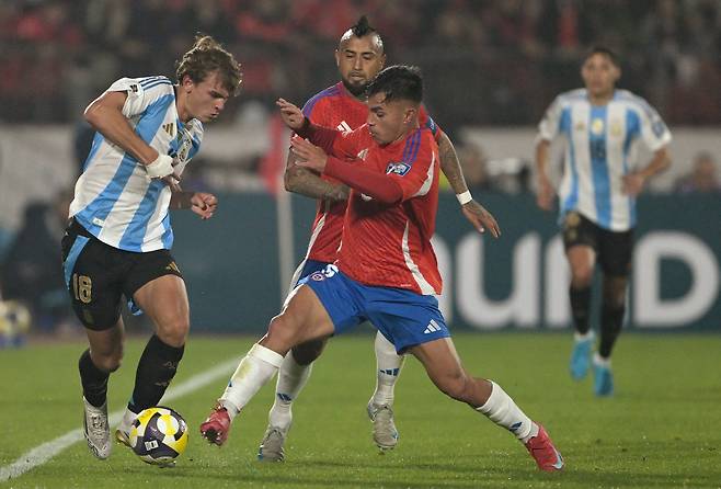 Argentina's midfielder #18 Nico Paz fights for the ball with Chile's midfielder #06 Vicente Pizarro and midfielder #08 Arturo Vidal (back) during the 2026 FIFA World Cup South American qualifiers football match between Chile and Argentina at the Nacional Julio Martinez Pradanos stadium in Santiago, on June 5, 2025. (Photo by Rodrigo ARANGUA / AFP)<저작권자(c) 연합뉴스, 무단 전재-재배포, AI 학습 및 활용 금지>