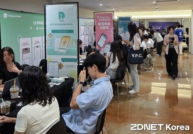 8월 22일 서울 마포구 ‘2025 너디너리 페스티벌-AI 대전환’ 행사장 지하 1층에서 관람객들이 대학생 앱 개발자들로부터 앱 소개를 받고 있다.