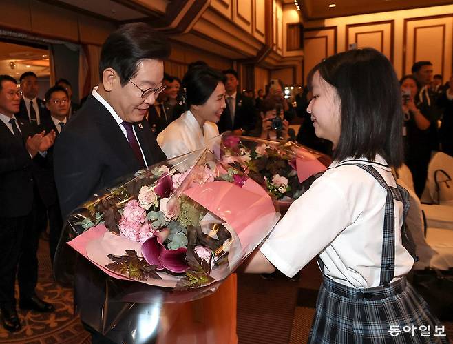 한일정상회담을 위해 일본을 방문한 이재명 대통령과 부인 김혜경 여사가 23일 도쿄의 한 호텔에서 열린 동포간담회에 참석해 꽃다발을 받고 있다. 도쿄=송은석 기자 silverstone@donga.com
