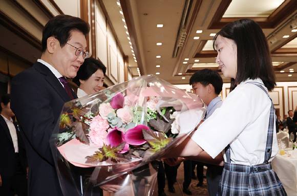 이재명 대통령과 김혜경 여사가 23일 일본 도쿄의 한 호텔에서 열린 재일동포 오찬 간담회에 참석해 화동으로부터 꽃다발을 받고 있다. [사진=연합뉴스]