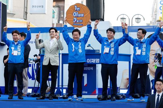 지난 5월 25일 이재명 더불어민주당 대통령 후보가 충남 천안시 신부문화거리를 찾아 문진석 충남도당 위원장으로부터 '1번 이재명 3표 더!'라고 적힌 호두과자 모양 피켓을 받은 뒤 들어보이고 있다. 뉴스1