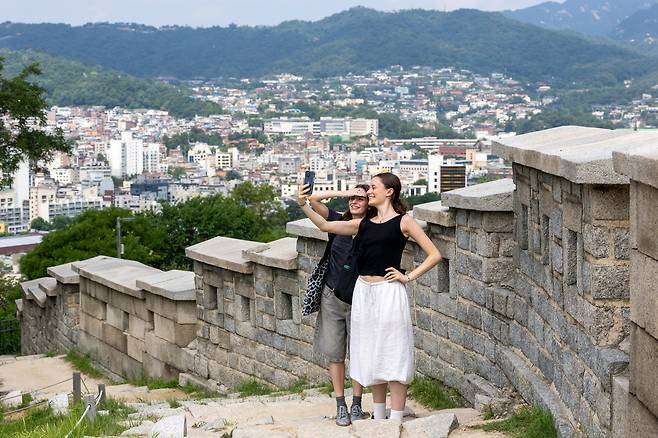 Foreign tourists take photos at Naksan Park in Seoul on Aug. 24, the dating spot of Rumi and Jinu in the Netflix animated film "KPop Demon Hunters." The movie’s success has drawn crowds to landmarks such as Naksan Park and N Seoul Tower./Kim Ji-ho