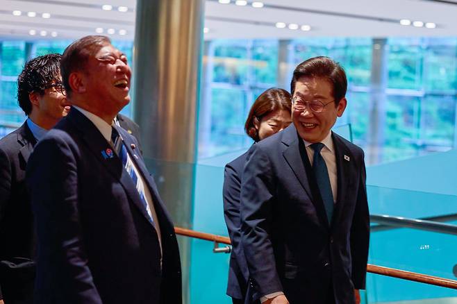 이재명 대통령이 23일 일본 도쿄 총리 관저에 도착해 이시바 시게루 일본 총리와 대화하며 이동하고 있다. /연합뉴스