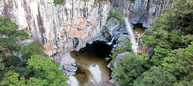 청하골 협곡 위에서 내려다본 관음폭포 일대의 모습. 내연산 풍경의 정점이다. 수직 벼랑이 마치 거대한 성벽 같다. 다리 아래로 쏟아지는 관음폭포가 6번째 폭포고, 구름다리 건너편 뒤쪽에 7번째 연산폭포가 있다. 내연산을 찾은 이들은 대개 여기까지 왔다가 되돌아 내려간다.