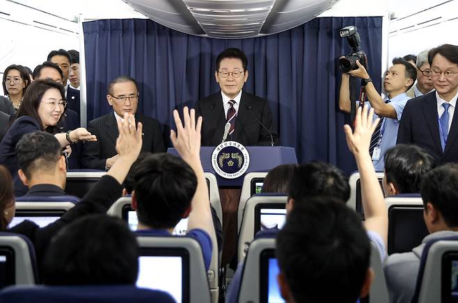 이재명 대통령이 24일(현지시간) 일본 도쿄 하네다공항 이륙 뒤 한미정상회담을 위해 미국 워싱턴DC로 향하는 공군 1호기 기내에서 연 기자간담회에서 취재진의 질문을 받고 있다.  [연합]