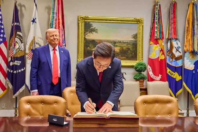 이재명 대통령이 25일(현지시간) 미국 워싱턴 DC 백악관에서 도널드 트럼프 미국 대통령이 지켜보는 가운데 방명록을 작성하고 있다. /사진=연합뉴스