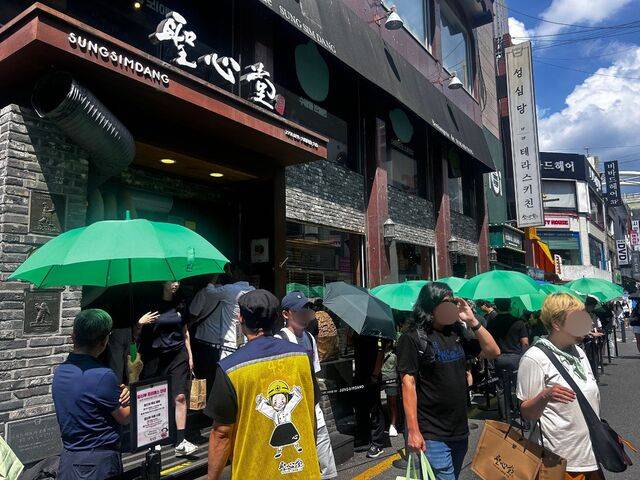 20일 오후 대전 중구 성심당 본점 앞이 인파로 북적이고 있다. 폭염이 계속되던 이날 강한 햇볕 아래 방문객들이 매장에서 제공한 초록색 우산을 받아들고 대기하고 있다.