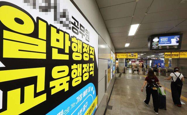 시민들이 25일 서울 노량진역 승강장에 설치된 공무원 시험 준비 학원 광고판 앞을 지나고 있다. 이날 통계청 국가통계포털 등에 따르면 지난 5월 기준 공무원 시험을 준비하는 청년(만20~34세) 수가 통계 작성 이래 최저 수준을 기록했다. 연합뉴스