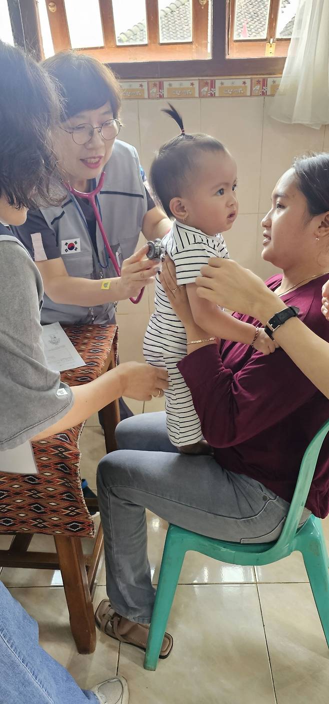지난 12일 인도네시아 GSJA 솔라 피데 파키산교회에서 부산 온천교회 의료선교팀 부단장인 정진아 권사(동아대의대 소아청소년과 교수)가 현지 주민의 아이를 진료하고 있다.  온천교회 제공
