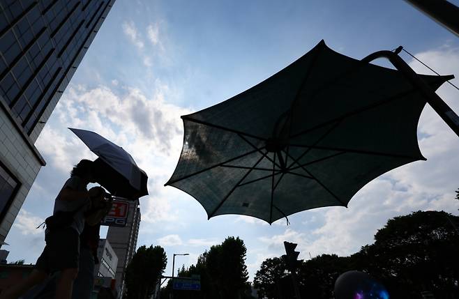 강남·서초·강동·송파구 등 서울 동남권에 폭염경보가 발효된 25일 오후 서울 송파구 석촌호수 사거리에서 양산을 쓴 시민들이 발걸음을 옮기고 있다. /사진=뉴시스