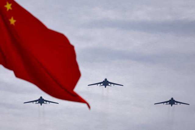 시안 H-6N 제트 폭격기가 24일 중국 베이징에서 열린 전승절 80주년 열병식 예행연습에서 중국 국기 뒤쪽으로 편대 비행하고 있다. 로이터연합뉴스