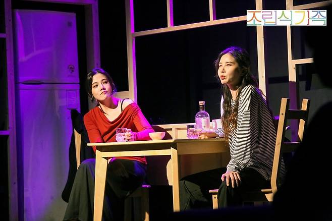 연극 ‘조립식 가족’의 한 장면. 보육원 출신 청년인 희정(김해나 분·오른쪽)과 오갈 데 없어 정식 집에서 얹혀 살고 있는 정미(윤신주 분)는 함께 술을 마시고 속 깊은 이야기를 털어놓으며 점차 가까워져 간다. (창크리에이티브 제공)