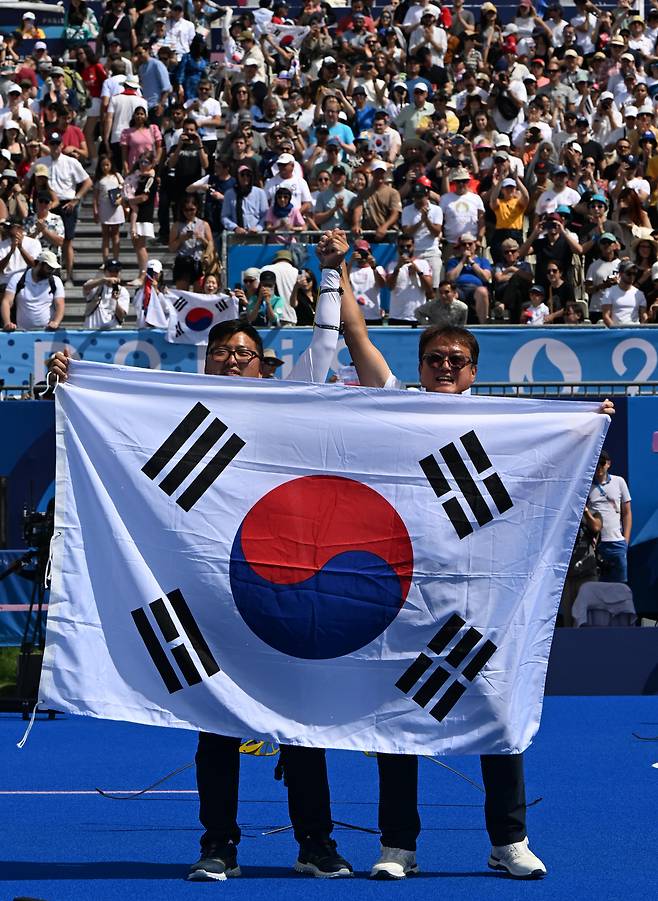 지난해 파리 올림픽 양궁 남자 개인 결승전서 금메달을 딴 김우진(왼쪽)이 박성수 감독과 세리머니를 하고 있다.   올림픽사진공동취재단