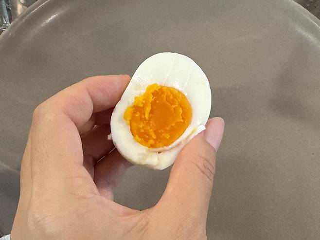 반으로 가른 계란을 들고 있는 손
