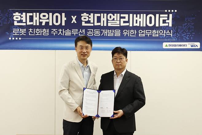 백익진(왼쪽) 현대위아 모빌리티솔루션사업부 상무와 이원해 현대엘리베이터 승강기사업본부장 상무가 28일 경기 의왕시 현대위아 의왕연구소에서 열린 ‘로봇 친화형 주차솔루션 공동개발을 위한 업무협약식(MOU)’에서 기념 사진을 촬영하고 있다. [현대위아 제공]