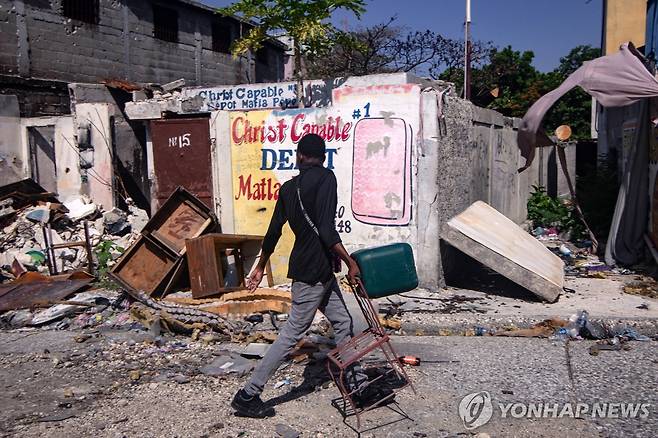 26일(현지시간) 아이티 수도 포르토프랭스에서 의자를 들고 귀가하는 주민 [포르토프랭스 EPA=연합뉴스. 재판매 및 DB 금지]