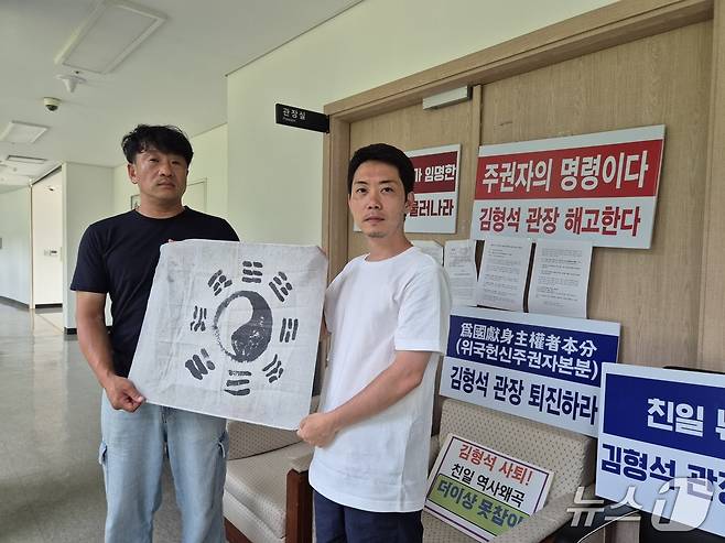 독립기념관장실 점거 농성 중인 김원일 씨(왼쪽)와 오주현 씨가 관장실 앞에서 태극기를 들고 역사왜곡 청산 의지를 다졌다. /뉴스1