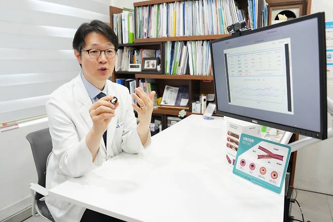 이치훈 세실내과 원장이 커프리스 활동 혈압 측정기  ‘카트비피 프로’를 들어 보이며 고혈압 관리 전략을 설명하고 있다.