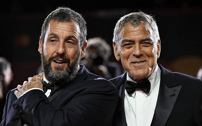 영화 ‘제이 캘리’에서 주인공 제이 캘리 역을 맡은 배우 조지 클루니(오른쪽)과 매니저 론 역을 열연한 배우 아담 샌들러가 28일(현지시간) 베니스영화제에 참석해 레드 카펫을 밟은 모습. [EPA·연합뉴스]