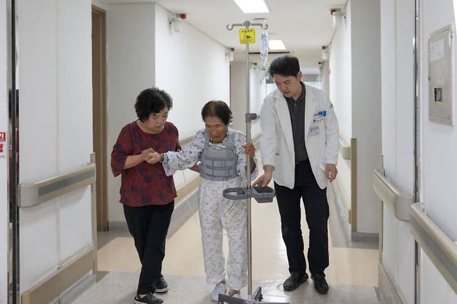 수술을 이겨낸 97세 할머니 환자가 집도의 석상윤 과장(오른쪽)과 함께 한발 한발 천천히 걸어보고 있다. [사진=부산 부민병원]