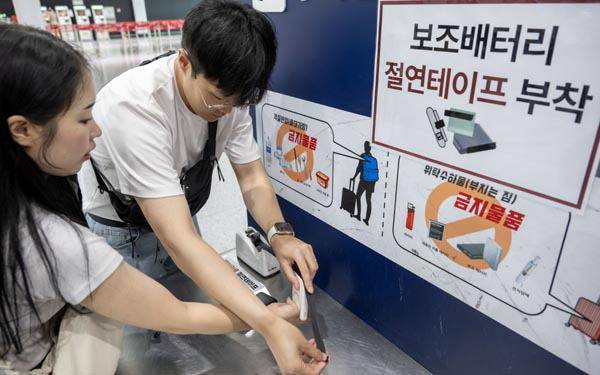 1일 김해국제공항 수하물 정리대에서 탑승객들이 보조배터리에 절연테이프를 붙이고 있다. 이원준 기자 windstorm@kookje.co.kr