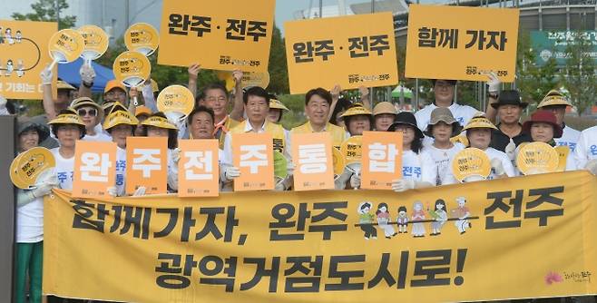 ▲우범기(가운데) 전주시장과 남관우(가운데 왼쪽) 전주시의회 의장을 비롯한 관계자들이 7월 28일 전북 전주시 호남제일문 사거리에서 열린 ‘완주·전주 통합 염원을 담은 대규모 출근길 홍보 캠페인’에 참석해 홍보전을 펼치고 있다./사진=뉴시스