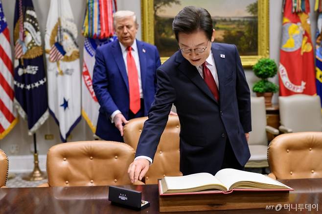 (워싱턴=뉴스1) 류정민 특파원 = 지난 8월 25일(현지시간) 이재명 대통령이 한미정상회담에 앞서 미 백악관 루즈벨트룸에서 방명록에 서명하려고 펜을 잡으려는 순간 도널드 트럼프 미국 대통령이 뒤에서 의자를 당겨 주고 있다. 2025.08.31(백악관 제공. 재판매 및 DB금지)  Copyright (C) 뉴스1. All rights reserved. 무단 전재 및 재배포,  AI학습 이용 금지. /사진=(워싱턴=뉴스1) 류정민 특파원