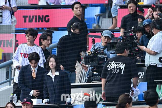 ▲ 관중석에는 김지훈(왼쪽), 임지연이 이정재의 시구 연기에 맞춰 촬영을 이어가고 있다. 관중석 또한 어수선한 상황.