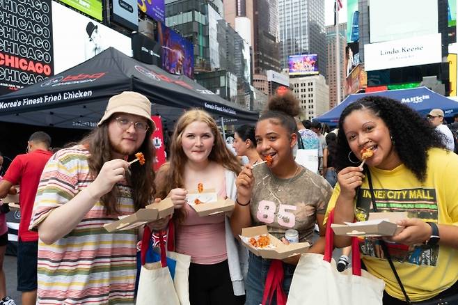 지난 7월 뉴욕 타임스스퀘어에서 열린 시식 행사에서 현지 시민들이 BBQ 치킨을 맛보고 있다. 제너시스BBQ 제공