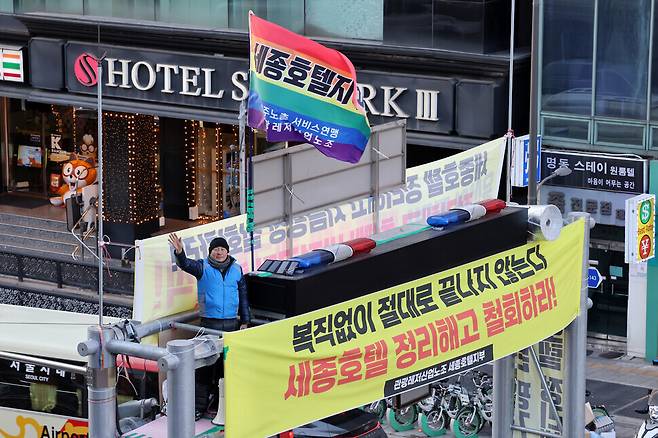 민주노총 서비스연맹 관광레저산업노조의 고진수 세종호텔지부장이 2025년 2월13일 서울 중구 명동역 1번 출구 앞 도로 위에 설치된 10여ｍ 높이 지하차도 진입 차단시설 위에 올라 고공농성을 벌이고 있다. 류우종 기자