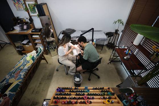 A person receives a tattoo in a studio in Seoul in 2021. [YONHAP]