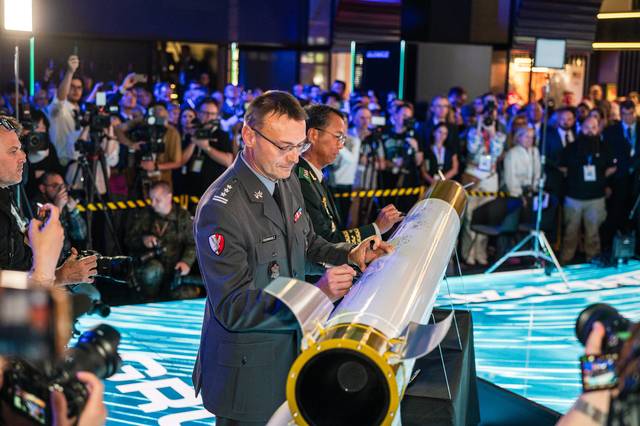 한국과 폴란드 양국 정부·군·업계 관계자들이 2일(현지시간) 폴란드 키엘체 국제 방위산업 전시회(MSPO 2025)에서 열린 천무 유도탄 생산을 위한 현지 합작법인 계약식에서 성공적인 방산협력을 축하하며 천무 모형탄에 서명했다. 한화에어로스페이스 제공