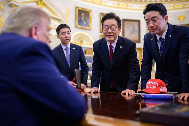President Lee Jae Myung, second from right, and presidential chief of staff Kang Hoon-sik, far right, speak with U.S. President Donald Trump, far left, who is seated at the Resolute Desk in the Oval Office of the White House in Washington on Aug. 25. [THE WHITE HOUSE]