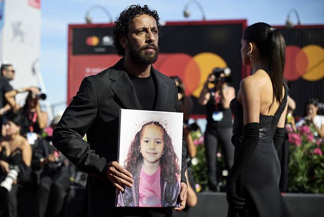 “이 소녀를 기억해주세요” 팔레스타인 배우 모타즈 말헤스가 3일(현지시간) 이탈리아 베니스에서 열린 제82회 베니스영화제 현장에서 영화 <힌드 라잡의 목소리>의 실제 주인공 라잡의 사진을 들고 있다. EPA연합뉴스