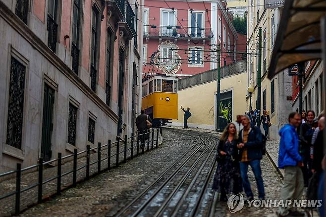 지난 2023년 11월 한 남성이 포르투갈 리스본에서 '글로리아' 노선을 운행하는 푸니쿨라 전차를 사진에 담고 있다. [AFP=연합뉴스 자료사진]