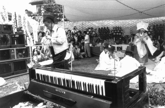 Nam June Paik performs in a shamanistic ritual-style show titled “A Pas de Loup: De Séoul à Budapest” at Gallery Hyundai’s courtyard on July 20, 1990. [GALLERY HYUNDAI]