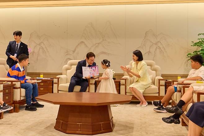 이재명 대통령이 지난 4일 서울 용산 대통령실 청사에서 열린 어린이 초청 행사에서 참석자에게 사인이 담긴 책을 선물하고 있다. 뉴스1