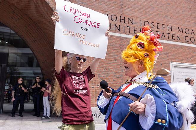 도널드 트럼프 미국 대통령으로 분장한 한 사람이 지난 7월 21일(현지시간) 매사추세츠주 보스턴의 존 조지프 모클리 연방 법원 밖에서 시위대와 교류하고 있다. 이날 하버드대학교 측 변호인단은 연방 법정에서 연방 정부가 20억 달러가 넘는 보조금과 계약을 동결한 것은 위법이며 철회돼야 한다고 주장했다.[게티이미지]