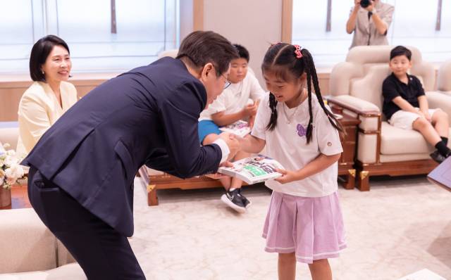 이재명 대통령과 김혜경 여사가 4일 서울 용산 대통령실 청사에서 열린 어린이 초청 행사에 참석한 어린이에게 책을 선물하고 있다. 연합뉴스