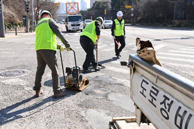 경기 수원의 한 도로에서 도로보수원들이 포트홀(도로 파임) 보수 작업을 마무리하고 있다. 수원시가 제공한 보도자료 사진이며, 인터뷰한 도로보수원들과는 직접 관련 없다. 불이익을 우려해 실명 인터뷰도 할 수 없는 현실이 이들이 처한 상황을 보여준다.