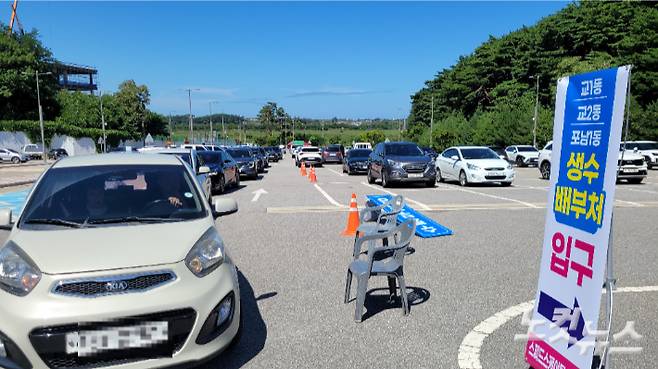 지난 5일 오후 강릉시 스피드스케이팅경기장 주차장에 마련한 '드라이브 스루'를 통해 생수를 받으러 온 차량들이 늘어선 모습. 전영래 기자